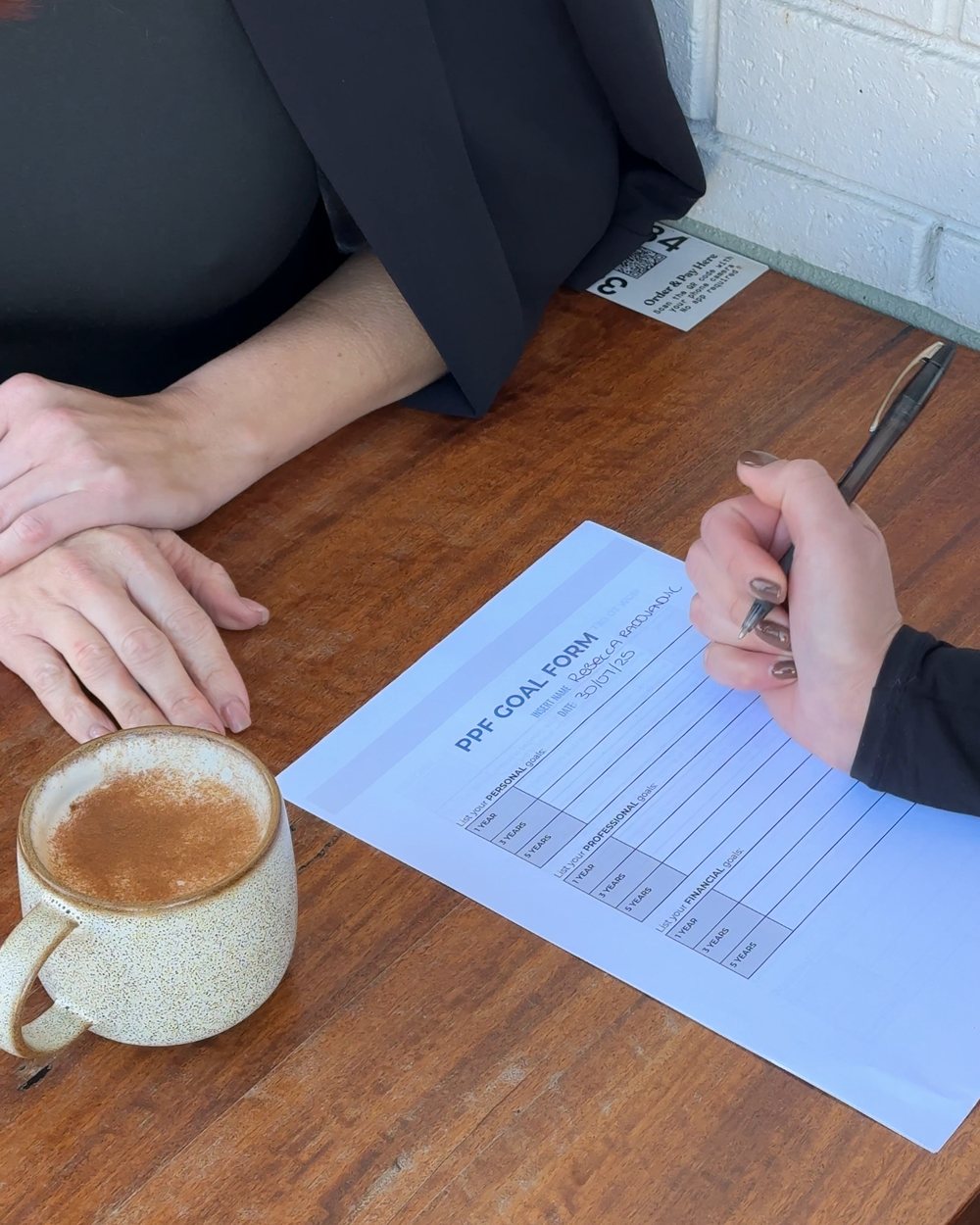 A stylist filling in her personal, professional and financial goal form over coffee